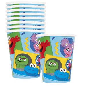 May include: A stack of light blue paper cups and one individual cup featuring Sesame Street characters including Elmo, Abby Cadabby, Oscar the Grouch, and Cookie Monster. The design includes yellow zigzag lines and the text 2026 Sesame Workshop.