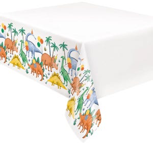 May include: White rectangular tablecloth with a colorful border featuring various dinosaurs, palm trees, and balloons. The dinosaurs are in shades of orange, yellow, green, and blue, with party hats. The tablecloth is suitable for a dinosaur-themed party.
