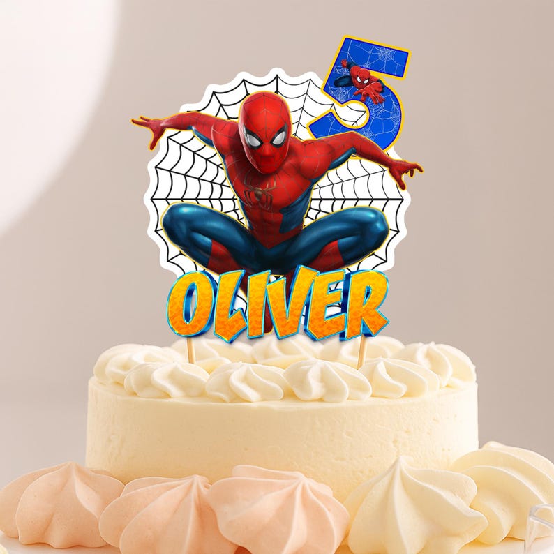 Może przedstawiać: Tort urodzinowy z motywem Spider-Mana. Ozdoba na tort przedstawia czerwoną i niebieską postać Spider-Mana, cyfrę 5 oraz imię "Oliver" w pomarańczowych i niebieskich literach. Tort jest pokryty białym lukrem i ozdobiony r&oacute;żowymi i białymi bezami.