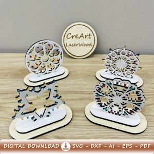 Può includere: Quattro decorazioni in legno tagliate al laser con disegni intricati. Le decorazioni includono una stella con luci a corda, un design circolare e altre due forme geometriche. Le decorazioni sono su una superficie di legno. Il testo "CreArt LaserWood" è visibile.