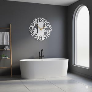 May include: A white, oval-shaped bathtub is the focal point of a modern bathroom. A decorative white clock with a tree design hangs on the gray wall. The clock has gold-colored hands. A wooden towel rack and a black faucet are also visible.