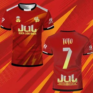 May include: A red short-sleeved t-shirt featuring a graphic print with the text JUL RIEN 100 RIEN on the front and the name TOTO with the number 7 and the text JUL on the back. The design includes an alien icon, a logo, and white accents.