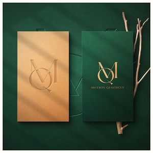 May include: Two business cards with the "Motion Quotient" logo. One card is gold with an embossed logo, and the other is dark green with the logo and text in gold. The background is a dark green.