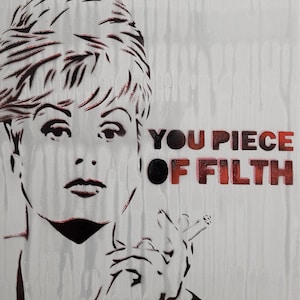 May include: A stencil art piece featuring a woman's portrait with the text "YOU PIECE OF FILTH" in red and black. The woman is depicted with short hair and is holding a cigarette.