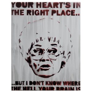 May include: A white canvas print with a stencil portrait of a woman wearing glasses. The dark red text says, "YOUR HEART'S IN THE RIGHT PLACE... BUT I DON'T KNOW WHERE THE HELL YOUR BRAIN IS."
