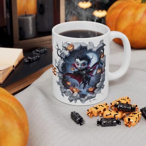 Peut inclure: Tasse à café en céramique blanche avec un motif sur le thème d'Halloween. La tasse présente un vampire de dessin animé sortant d'un mur brisé, entouré de citrouilles et d'une pleine lune. Le mot "Coffee" est imprimé sur le côté.