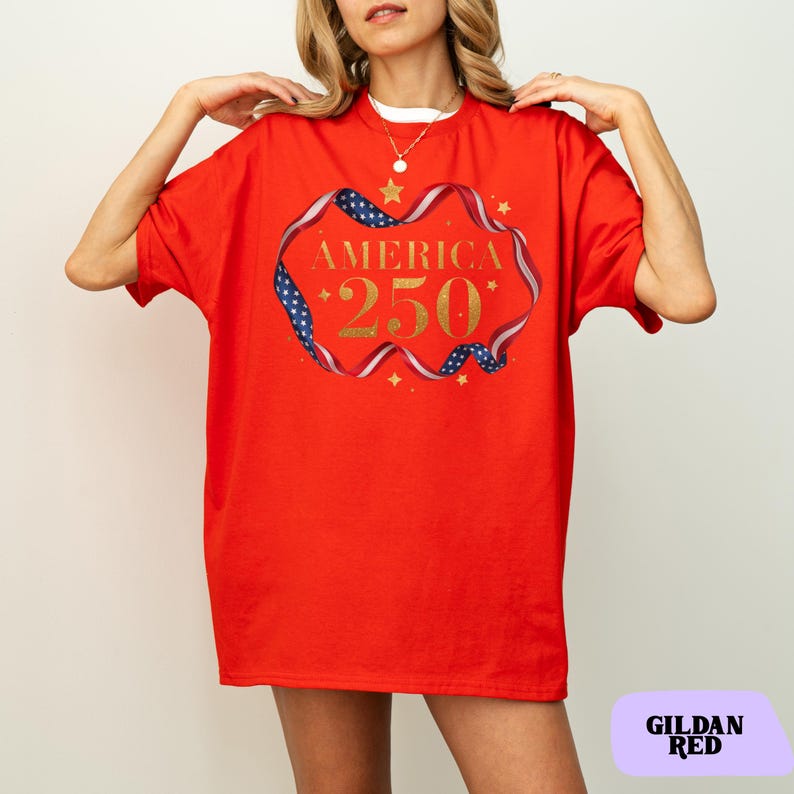 Bold gold glitter style America 250 typography framed with flowing USA flag ribbon and stars. Printed on soft premium cotton tees for adults, youth and toddlers. Unisex relaxed fit, breathable and durable for all day comfort. Ideal for Independence Day, patriotic parades, fireworks nights, family matching outfits, USA 250 celebrations and summer events.
