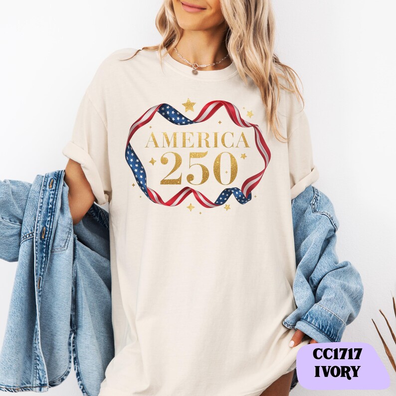 Bold gold glitter style America 250 typography framed with flowing USA flag ribbon and stars. Printed on soft premium cotton tees for adults, youth and toddlers. Unisex relaxed fit, breathable and durable for all day comfort. Ideal for Independence Day, patriotic parades, fireworks nights, family matching outfits, USA 250 celebrations and summer events.