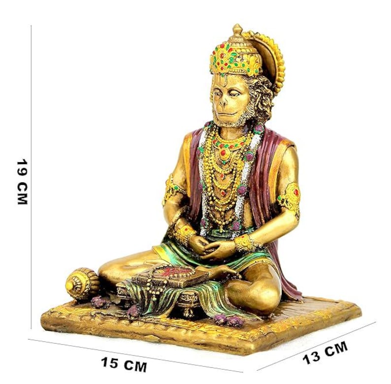 May include: A gold-colored Hanuman statue, seated with hands in a meditative pose. The statue is adorned with a jeweled crown and layered necklaces. The base measures 15 cm x 13 cm, and the statue is 19 cm tall.