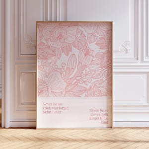 Puede incluir: Un cuadro enmarcado con un diseño floral rosa sobre un fondo blanco. La obra de arte incluye el texto "Never be so kind, you forget to be clever" y "Never be so clever, you forget to be kind". La impresión se muestra en una habitación con paredes blancas y suelo de madera.