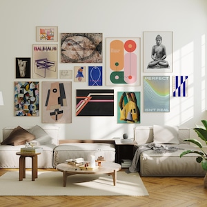 May include: A gallery wall featuring various framed art prints in a living room setting. The artwork includes abstract designs, geometric shapes, and a Buddha statue. The color palette includes beige, black, blue, and orange.