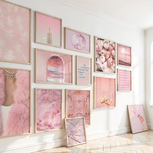 Può includere: Una collezione di stampe artistiche incorniciate a tema rosa, con immagini di città, fiori e disegni astratti. Alcune stampe presentano testo, tutte esposte in cornici di legno su una parete bianca.