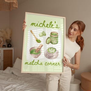 Peut inclure: Une affiche encadr&eacute;e sur fond vert clair avec des illustrations li&eacute;es au matcha. L'affiche comprend une cuill&egrave;re en bois, un fouet &agrave; matcha, une tasse de latte au matcha et un pot de matcha. Le texte "michele's matcha corner" est &eacute;crit en vert.