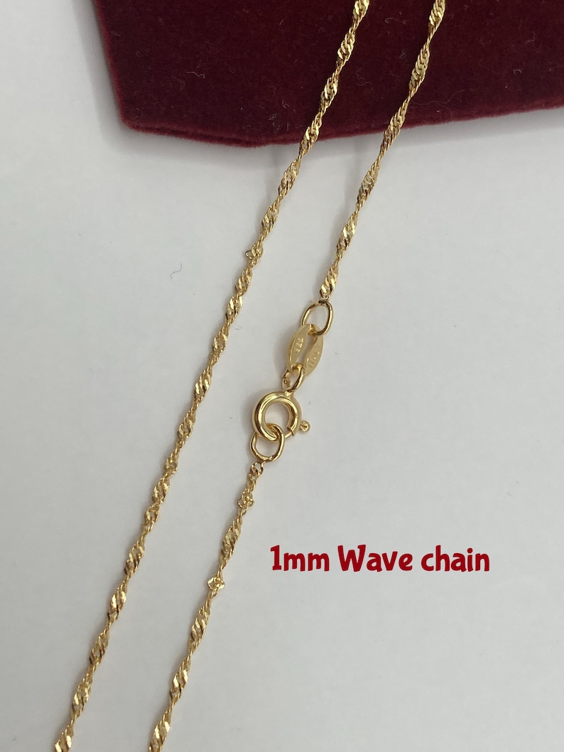 May include: A gold-colored 1mm wave chain necklace. The chain has a delicate, twisted design and a spring ring clasp. The text "1mm Wave chain" is visible in the image.