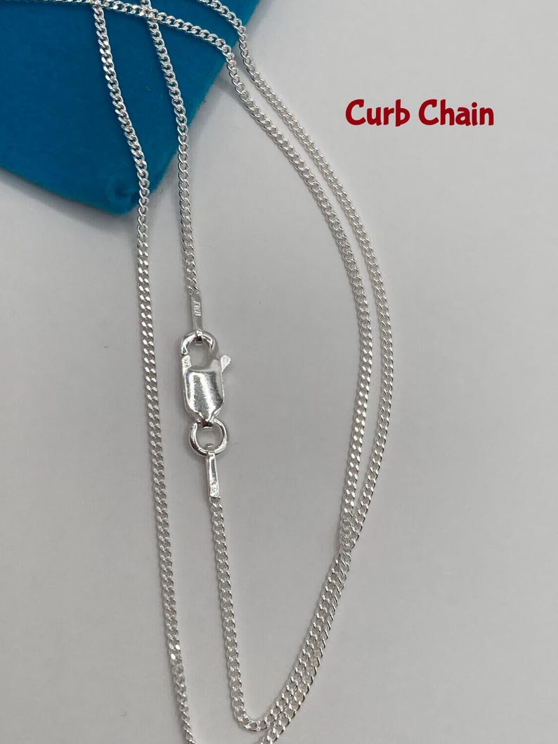 May include: A silver curb chain necklace with a lobster clasp. The chain is displayed against a blue background. The words "Curb Chain" are written in red.