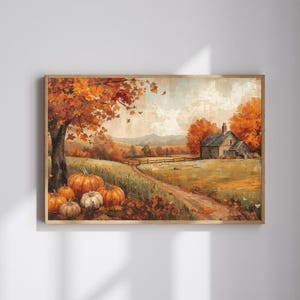 Puede incluir: Una impresión en acuarela enmarcada representa un sereno paisaje otoñal. Un camino de tierra conduce a una casa, con calabazas en primer plano. La escena está llena de follaje naranja y amarillo, creando un ambiente cálido.