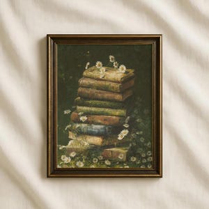 Puede incluir: Una impresión de arte mural rectangular enmarcada que muestra una pila vertical de libros antiguos desgastados y multicolores sobre una superficie verde oscuro, rodeada de numerosas flores pequeñas de margaritas blancas con centros amarillos, en un marco marrón.