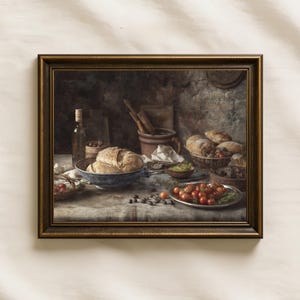 Puede incluir: Un bodegón enmarcado que representa una escena de cocina rústica con una hogaza de pan en un cuenco azul, una botella de aceite, un cuenco de tomates cherry y varios utensilios de cocina. La composición presenta tonos cálidos y terrosos.