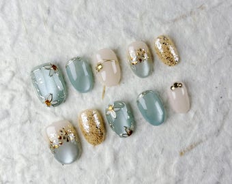 Zarte kurze ovale Presse auf den Nägeln in zartem Blau, Beige und Gold mit floralen Mustern. Perfekt für den Alltag und ungezwungene Zusammenkünfte