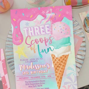 以下が含まれることがあります： 「THREE Scoops of Fun」と「Madisson's 3RD BIRTHDAY」の文字が入ったカラフルな招待状。3つのスクープ、振りかけ、星が付いたアイスクリームコーンのデザイン。招待状は装飾的なお皿の上にあります。