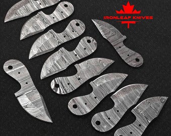 Peut inclure: Un ensemble de lames de couteau en acier de Damas avec un motif de grain de bois unique. Les lames sont de formes et de tailles variées, sur un fond sombre. Le logo Ironleaf Knives est visible en haut à droite.