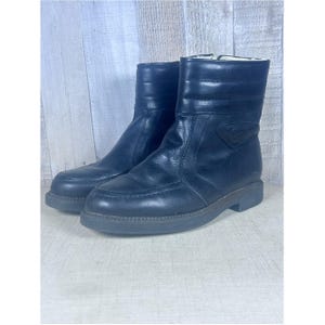 May include: A pair of black leather ankle boots featuring a quilted upper shaft, a rounded toe box with stitched detailing, and a low block heel. The boots have a smooth leather finish and a visible white lining at the top edge of the collar.
