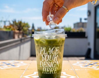 Durchsichtige Tasse Mockup — Hand lässt Eis in einen Matcha Latte PSD fallen