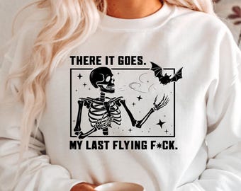 May include: White sweatshirt with a black graphic of a skeleton, bat, and the text "THERE IT GOES. MY LAST FLYING F*CK." The skeleton is holding a bat. The design is enclosed in a black rectangle.
