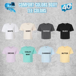 May include: A collection of eight short-sleeved boxy t-shirts in various colors including white, ivory, pepper, black, orchid, chalky mint, chambray, and butter. Each shirt is labeled with its respective color name in bold black text.