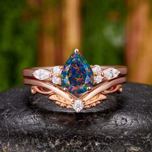 Conjunto de 2 anillos de compromiso con ópalo negro sintético talla pera de 6 x 8 mm, diseño de hojas y enredaderas en oro rosa con detalles de moissanita.