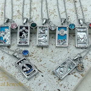 May include: A selection of silver tarot card pendant necklaces. The designs include The Empress, The Star, The Moon, The Sun, The Lovers, Strength, and Temperance. Each pendant has a coloured gemstone accent and hangs from a delicate chain.