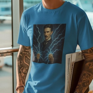 May include: A light blue t-shirt featuring a graphic of Nikola Tesla holding lightning bolts. The person in the image is wearing sunglasses and jeans. The person is holding a stack of papers.