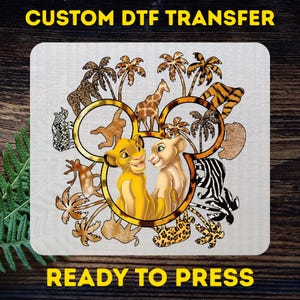 May include: A DTF transfer featuring a design with the text "CUSTOM DTF TRANSFER" and "READY TO PRESS". The design includes the Lion King characters, palm trees, and various animal prints, all within a Mickey Mouse-shaped frame.