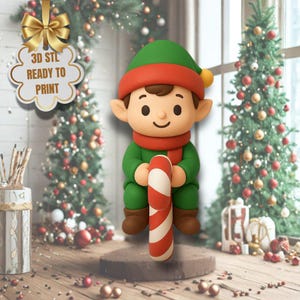 Peut inclure: Figurine d'elfe imprimée en 3D, vêtue de vert avec une écharpe et un chapeau rouges, tenant une canne en bonbon rouge et blanche. La figurine est sur une surface en bois, avec des arbres de Noël et des décorations en arrière-plan. Le texte sur une étiquette indique "3D STL READY TO PRINT".