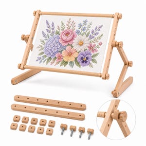 May include: A light-colored wooden embroidery frame stand holding a white fabric panel with a cross-stitched floral bouquet featuring pink, purple, blue, and white flowers. The set includes two additional wooden bars, ten square wooden nuts, and four metal bolts.