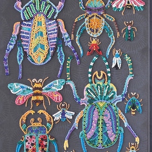 Può includere: Una collezione di opere d'arte di insetti in perline, tra cui scarabei e farfalle, in colori vivaci come blu, verde, giallo e rosa. Gli insetti sono disposti su uno sfondo grigio scuro, mostrando un'intricata lavorazione di perline.