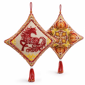 May include: Two diamond-shaped, embroidered ornaments. One features a red horse design, the other a geometric pattern in yellow, orange, and red. Both have beaded edges, red tassels, and hanging loops.