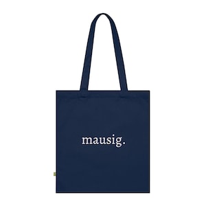 Pode incluir: Uma sacola tote azul marinho com um corpo retangular e duas alças longas. A palavra "mausig." é impressa em branco, centralizada na frente da sacola. A sacola é feita de um tecido resistente.