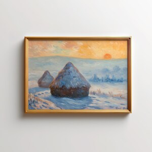 Puede incluir: Pintura de paisaje enmarcada con dos montones de heno cubiertos de nieve en una escena invernal. La obra de arte tiene un marco dorado y representa una puesta de sol con tonos naranja y amarillo. La pintura evoca una atmósfera serena y rural.