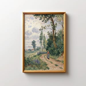 May include: A framed landscape painting featuring a dirt path winding through a green forest. A person in a dress and hat walks along the path. The background shows a body of water and a cloudy sky. The frame is gold.