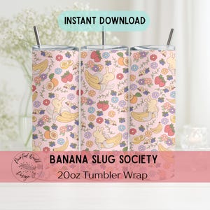 May include: A 20oz tumbler wrap with a pink background and a repeating pattern of bananas, strawberries, oranges, and flowers. The design includes the text "BANANA SLUG SOCIETY" and "20oz Tumbler Wrap". The tumbler has a straw.