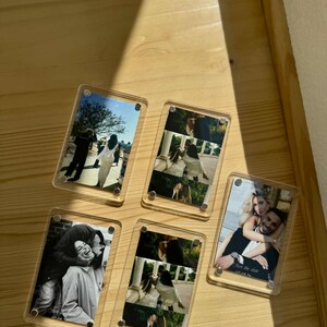 Puede incluir: Cinco bloques de fotos de acrílico transparente con imágenes de parejas. Las fotos son en blanco y negro y en color. Cada bloque tiene un pequeño cierre metálico en cada esquina. Algunos bloques tienen el texto "Save the date" y una fecha.