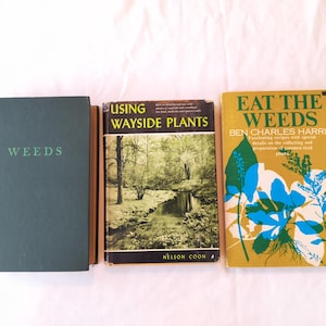 May include: Three hardcover books arranged side by side. The left book is dark green with the word WEEDS printed in light green. The middle book is titled USING WAYSIDE PLANTS by Nelson Coon, featuring a black and white landscape photograph. The right book is titled EAT THE WEEDS by Ben Charles Harris, featuring a gold cover with blue and green botanical illustrations.