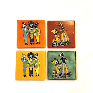 May include: A set of four square ceramic tiles featuring hand-painted illustrations of skeleton figures. Two tiles show three standing skeletons in colorful attire on orange and yellow backgrounds, while two show a kneeling skeleton proposing to another on red and green backgrounds.