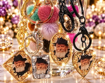 May include: A collection of keychains featuring portraits of a bearded person in a hat, encased in gold and silver leaf frames. The set includes diamond, rectangular, oval, and heart-shaped pendants with gold and black metal hardware.