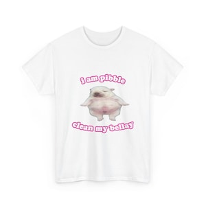 Pode incluir: Camiseta branca com uma imagem de desenho animado de uma criatura rechonchuda e o texto rosa "i am pibble clean my bellay". A camiseta é feita de um material macio, adequada para roupas casuais.