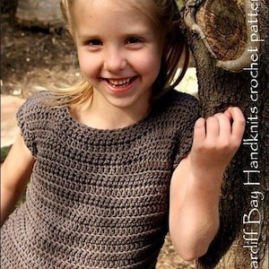 May include: A young girl wearing a brown crocheted top with short sleeves. The top has a simple design with horizontal rows of stitches.