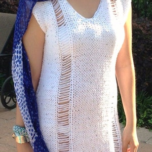 May include: A white crochet dress with a distressed design and a blue and white patterned scarf.