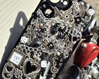 A dark, gothic-style phone case hand‑decorated with charms and resin details.