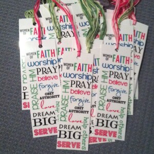 May include: A stack of white bookmarks with colorful text. The text includes the words "Faith", "Worship", "Pray", "Believe", "Forgive", "Obey Authority", "Love", "Dream Big", and "Serve".